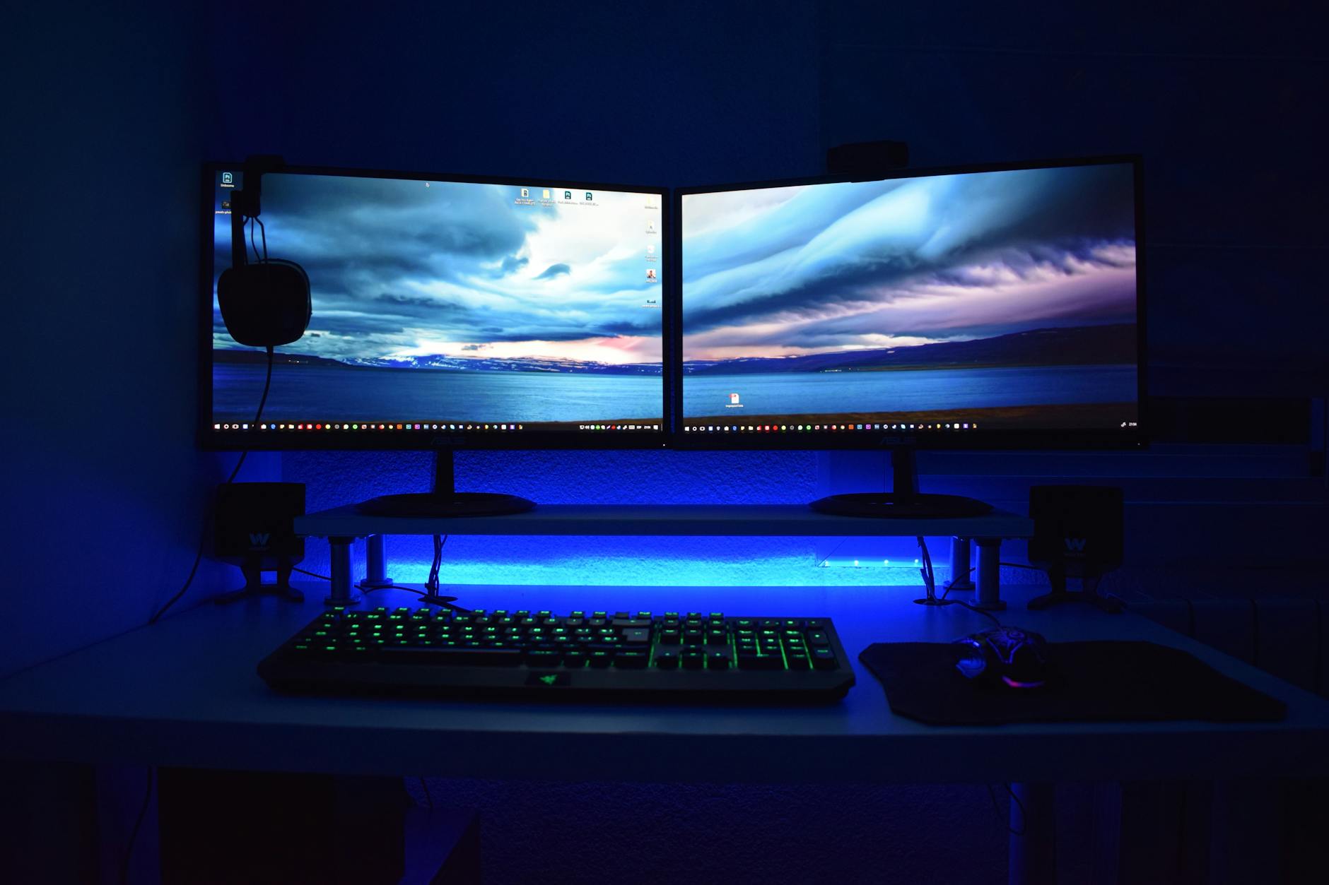 Image of two desktop monitors and a keyboard with blue background lights.